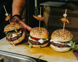 person holding burger with patty and cheese pub grub